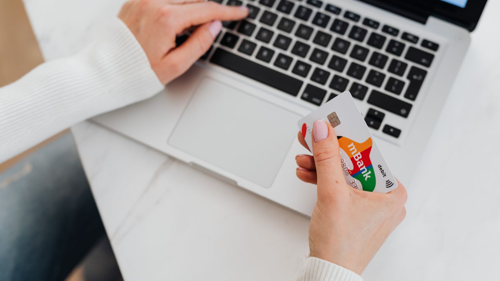 Person holding a bank card while opening an account on a laptop