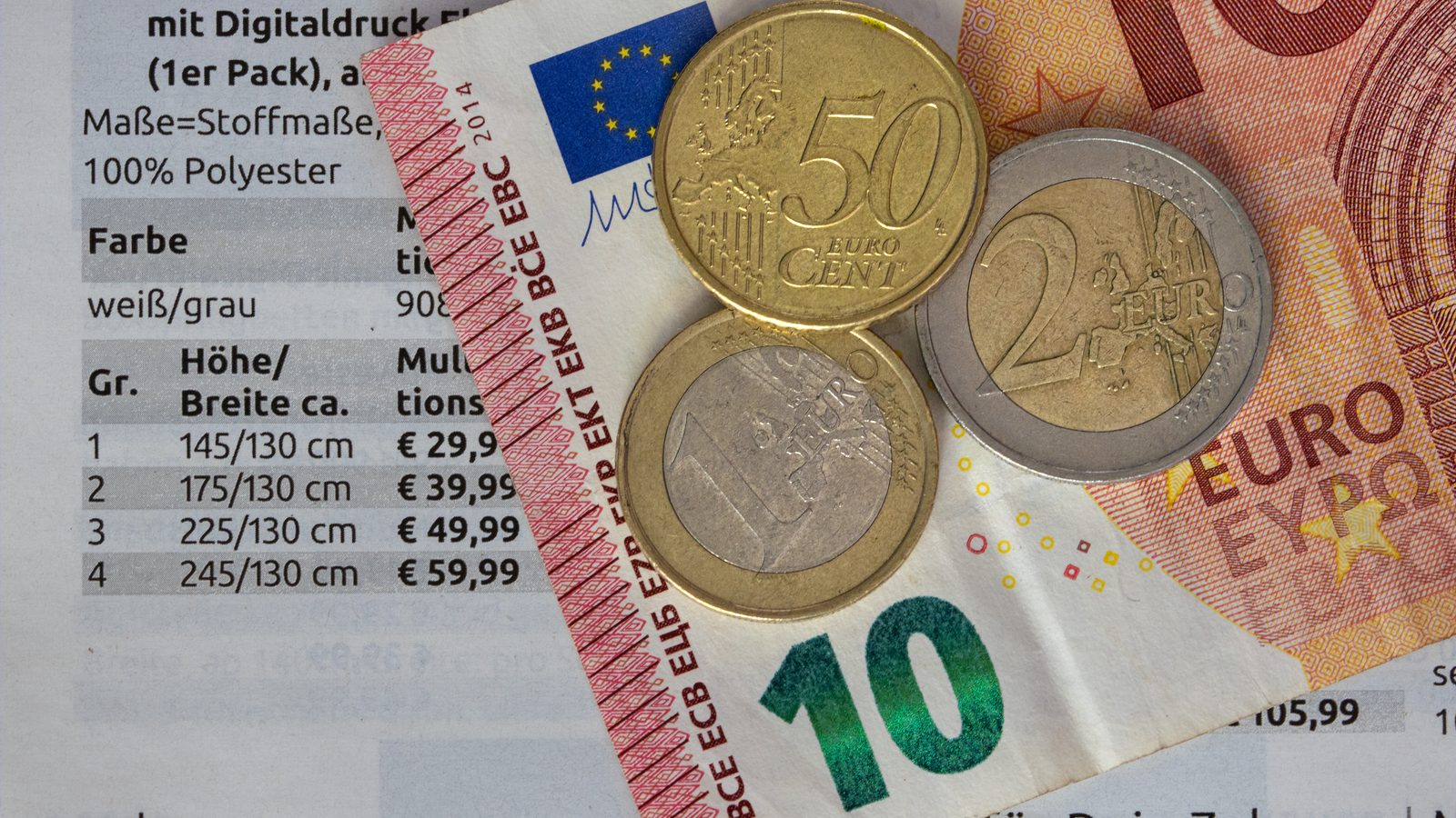 Euro notes and coins resting on a printed price list