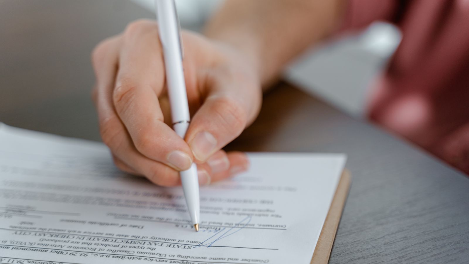 Hand signing an official company document with a ballpoint pen