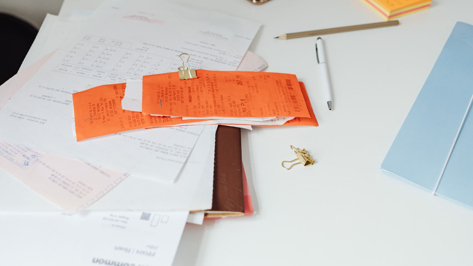 Invoices and receipts spread across a tidy desk with office stationery