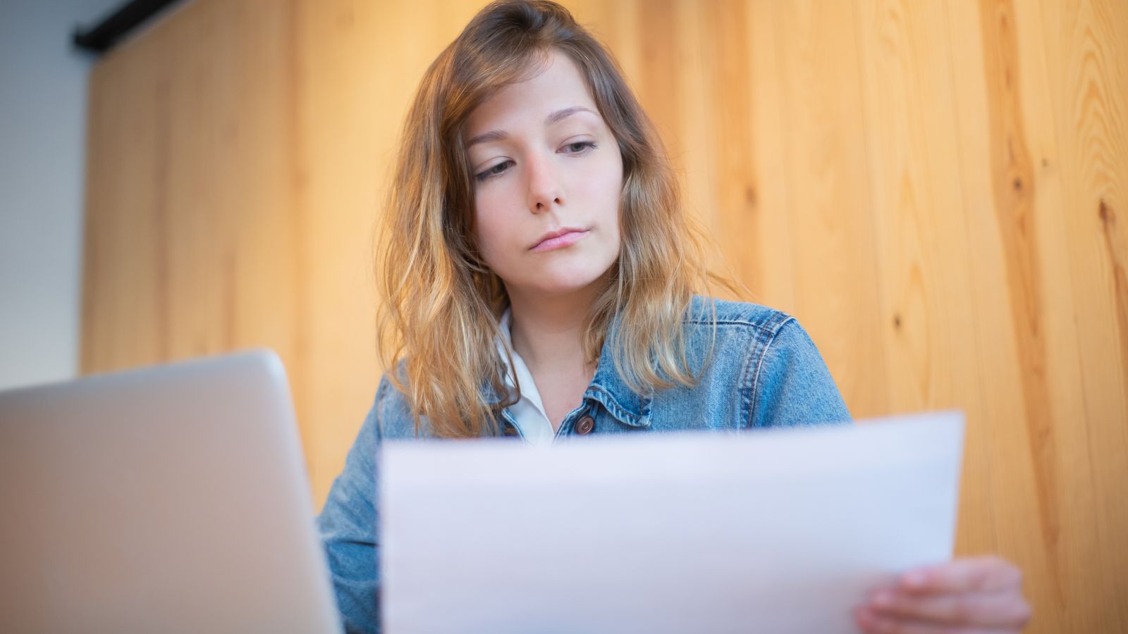 Self-employed woman going through her paperwork at a wooden table