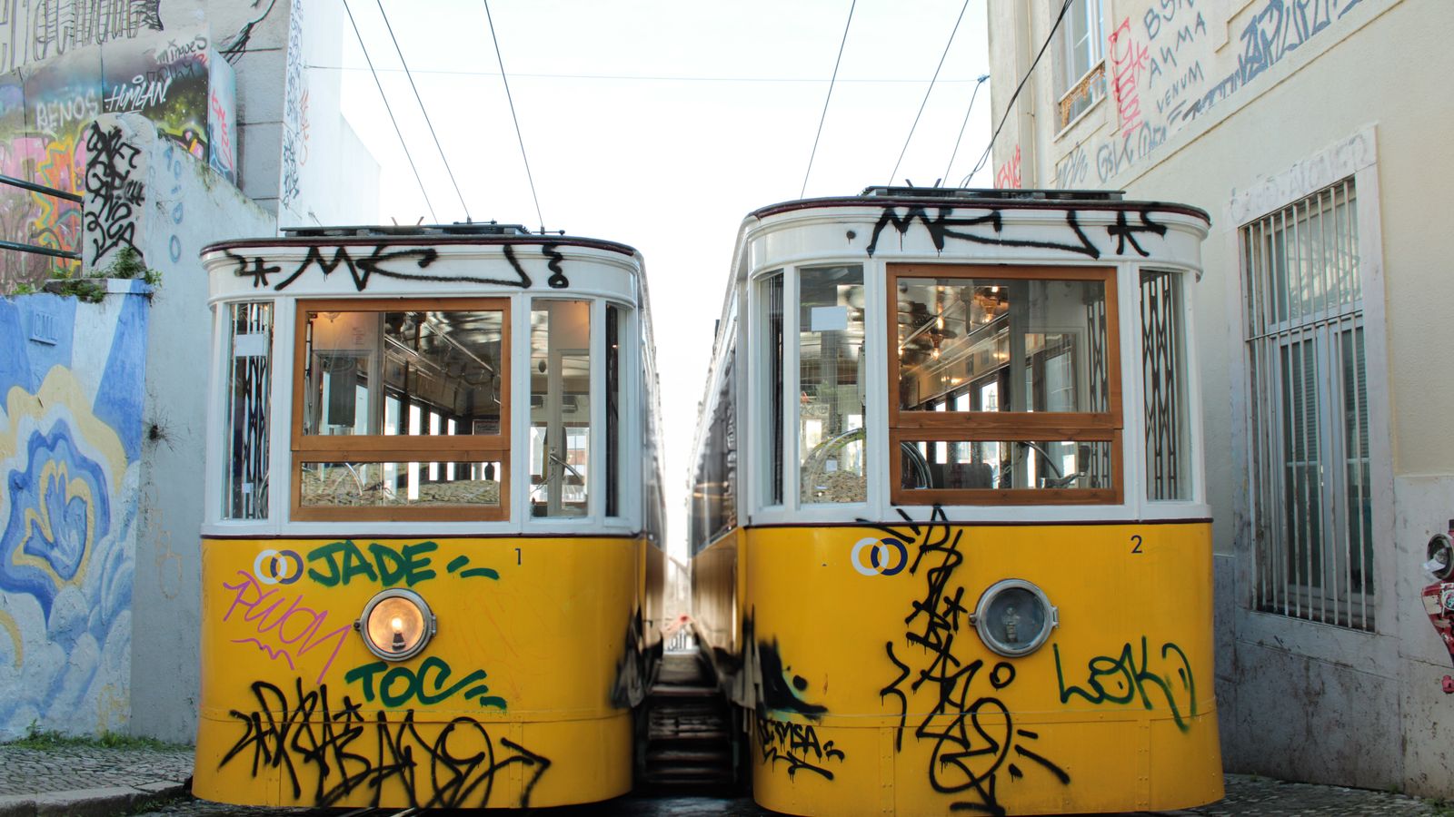Two yellow trams passing on a narrow street in Lisbon, Portugal