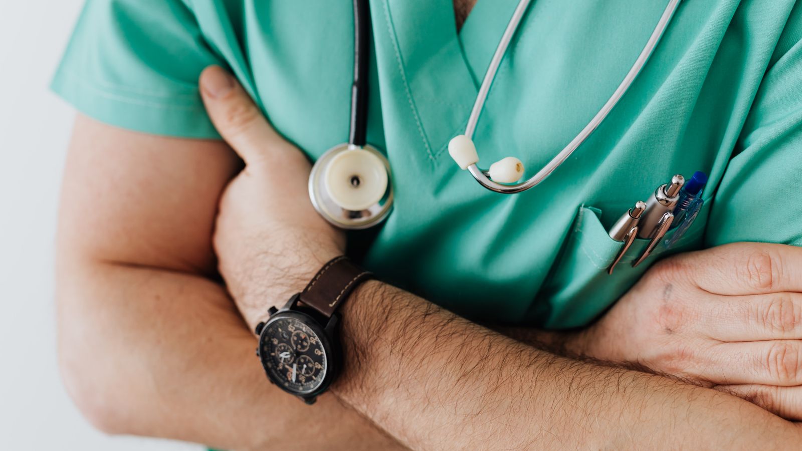 Healthcare worker in scrubs with a stethoscope in a hospital corridor