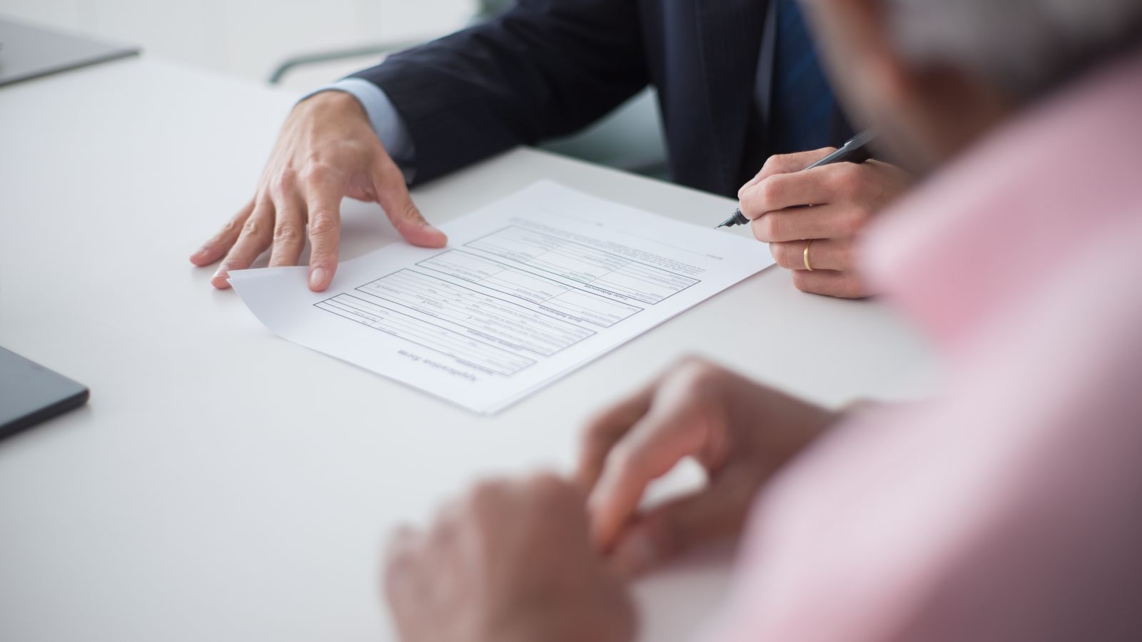 Two people signing company registration papers at a meeting