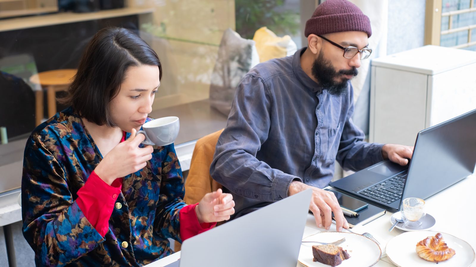 Two freelancers working on laptops in a café