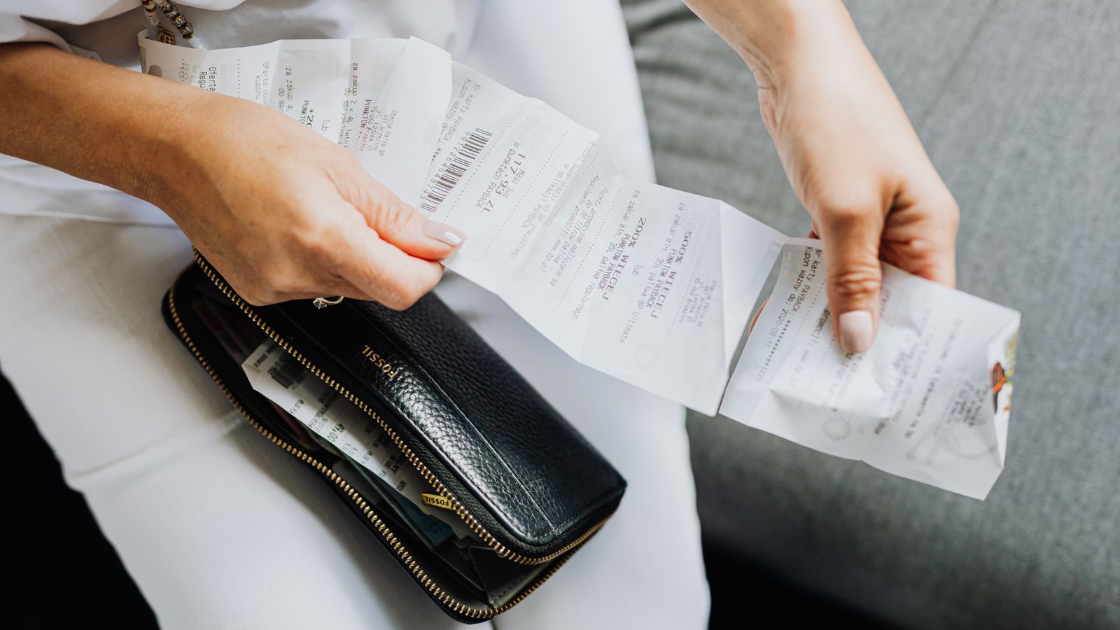 Hands sorting a handful of receipts taken from a wallet