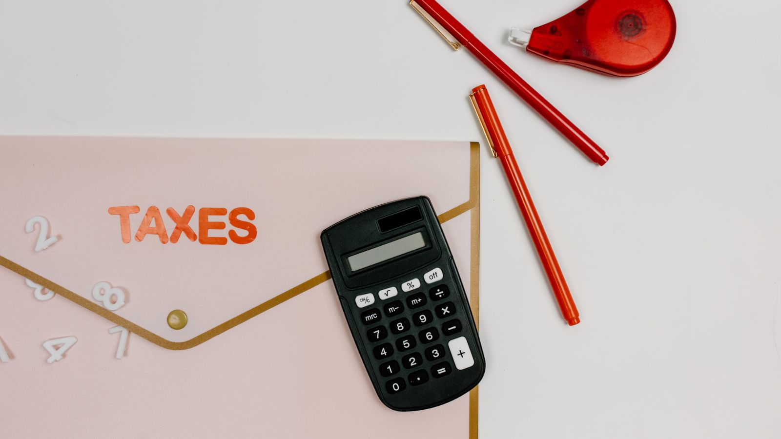 A calculator and pens beside a folder labelled Taxes
