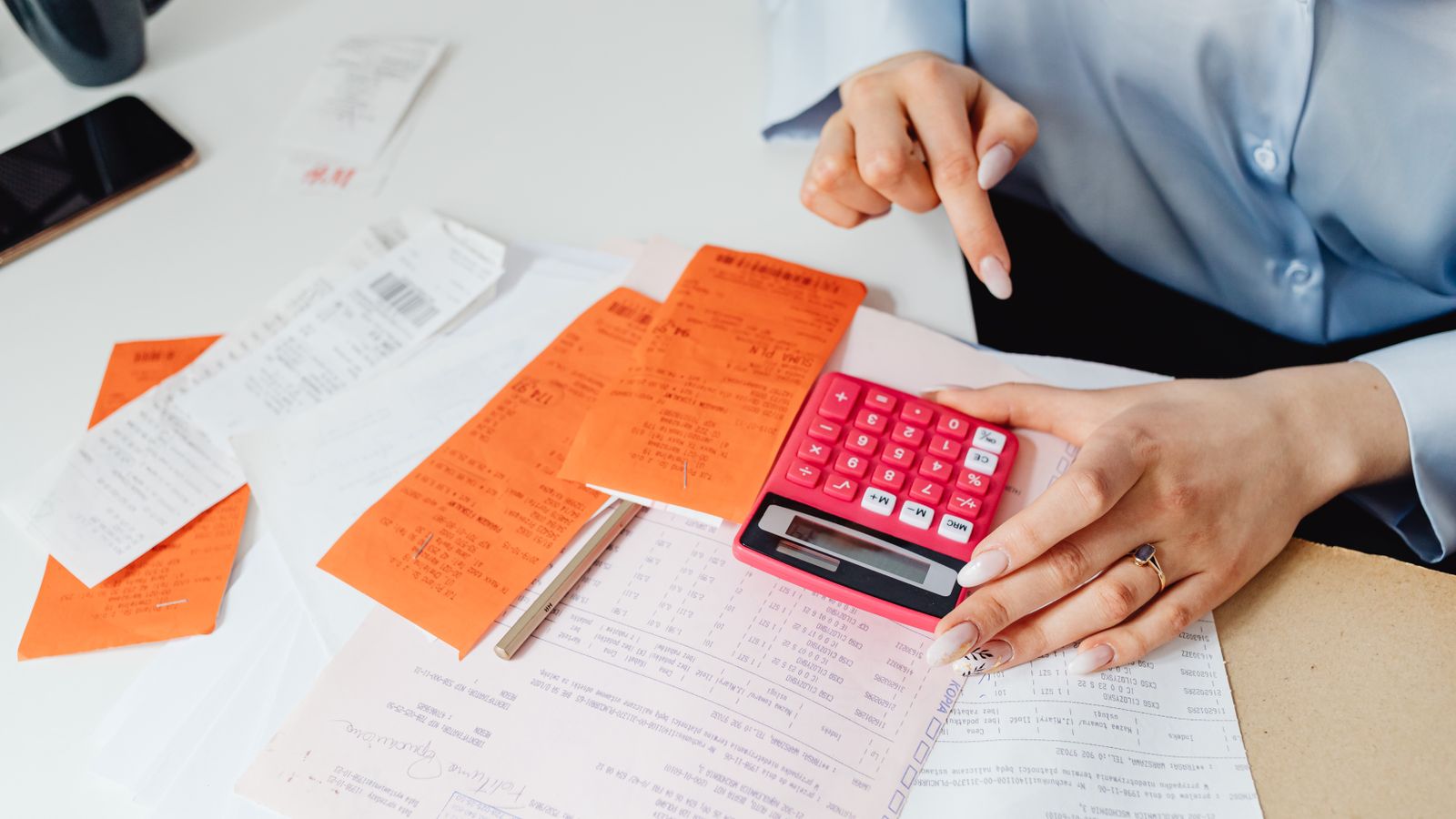 Business owner totalling up receipts on a calculator at a desk