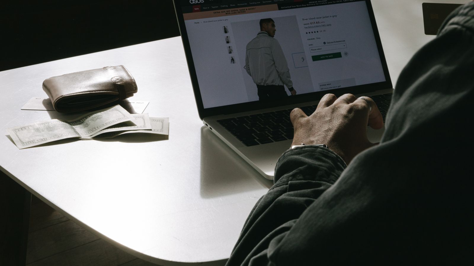 Man shopping online from home with his laptop and wallet on the table