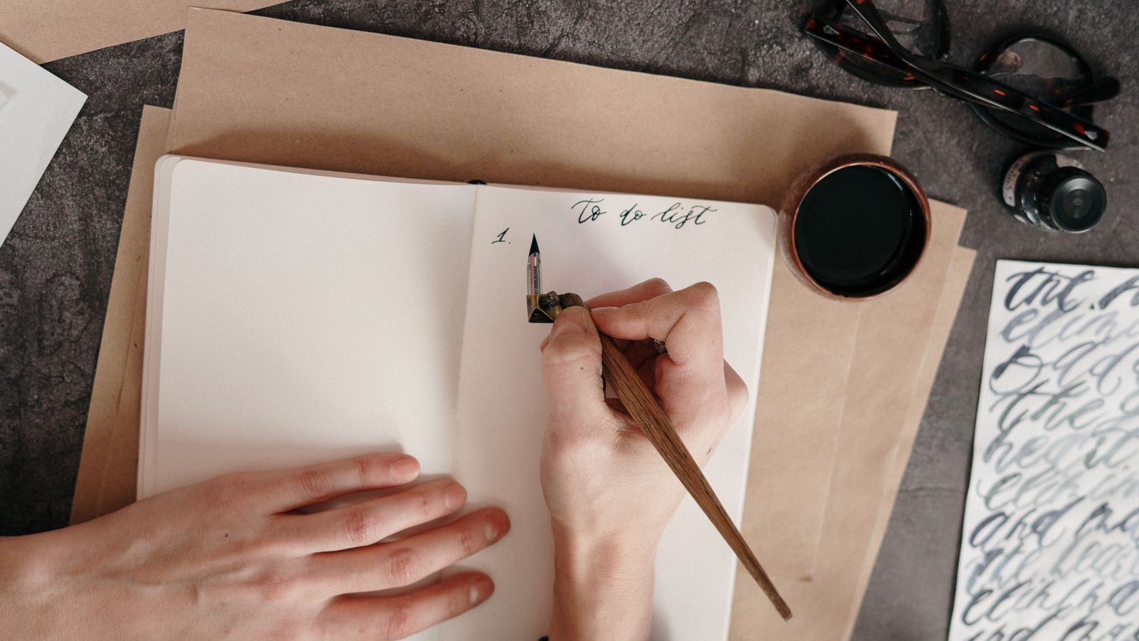 A handwritten to-do list on a desk with a pen and ink
