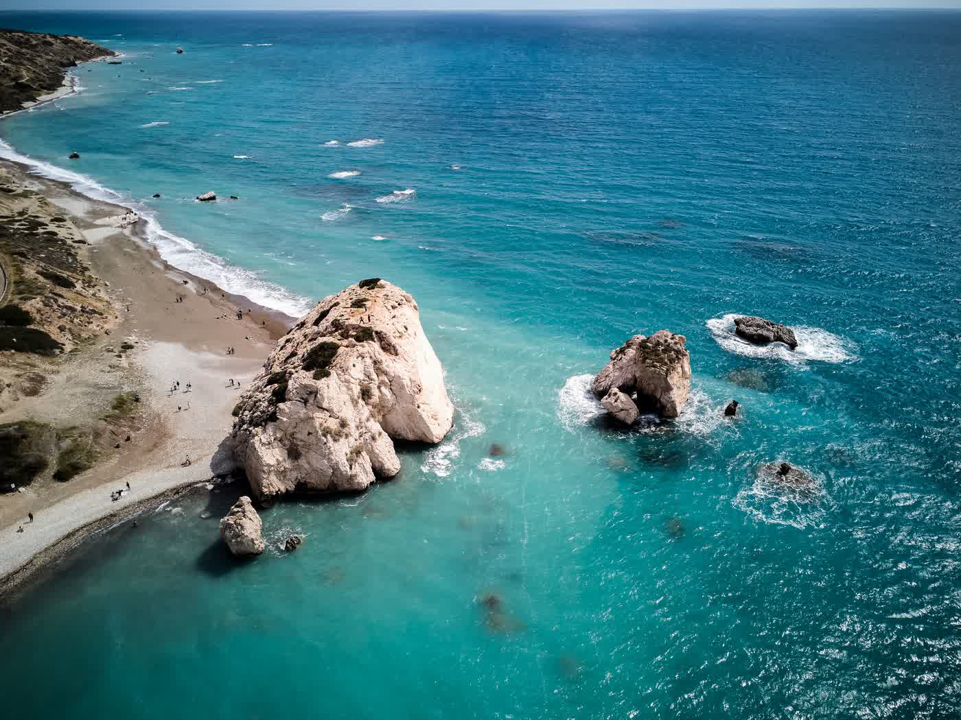 Aphrodite's Rock on the Paphos coast from the air, pale limestone stacks in bright turquoise water