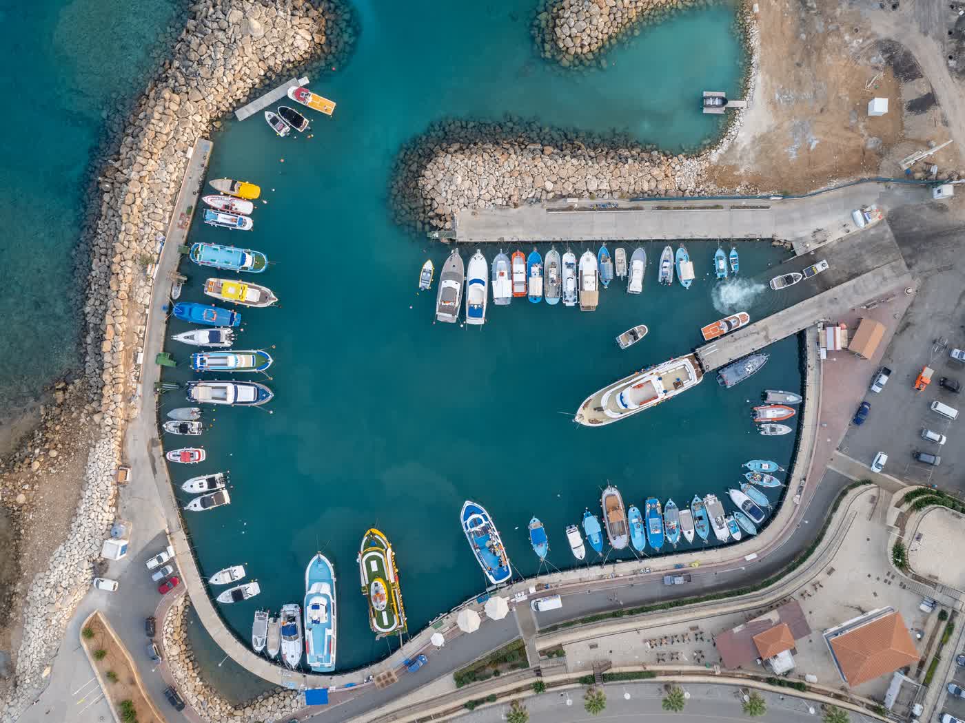 A small Cyprus harbour seen straight down from above, fishing boats and launches moored along every quay