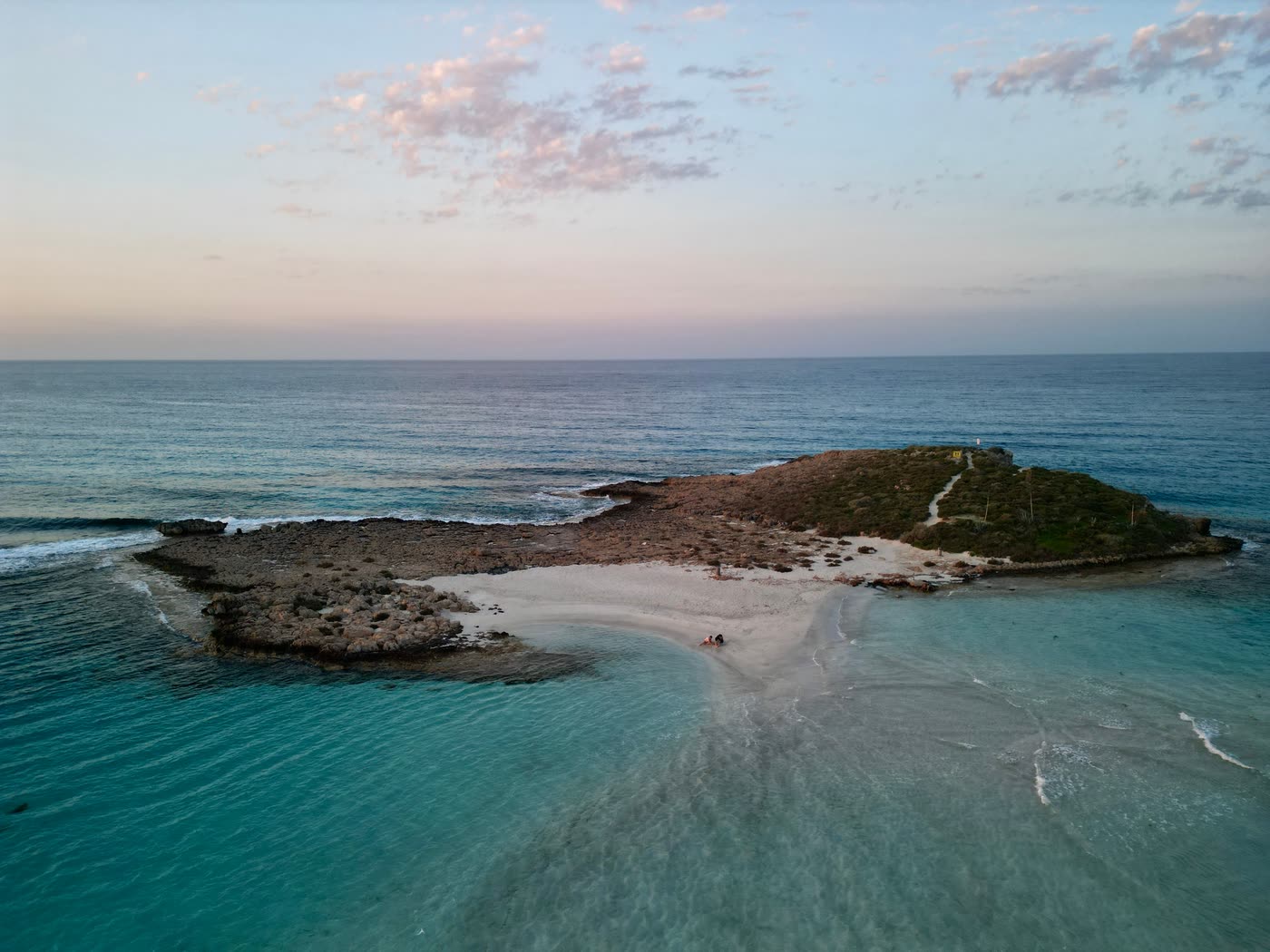 The islet off Nissi beach at dusk, joined to the shore by a pale sandbar in shallow turquoise water
