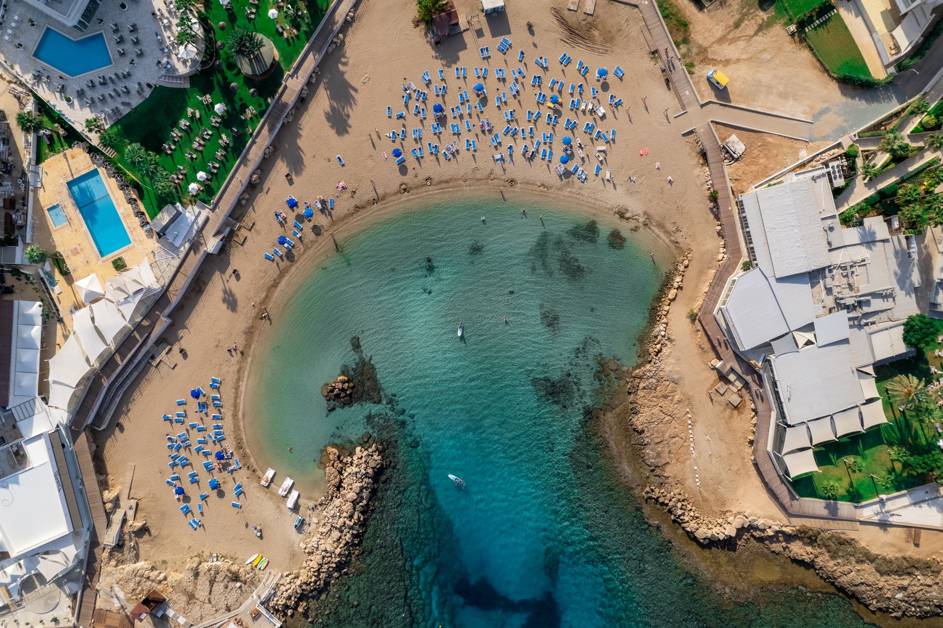 An aerial view of a beach resort at Paralimni in Cyprus, with rows of sun loungers on the sand and clear shallow water