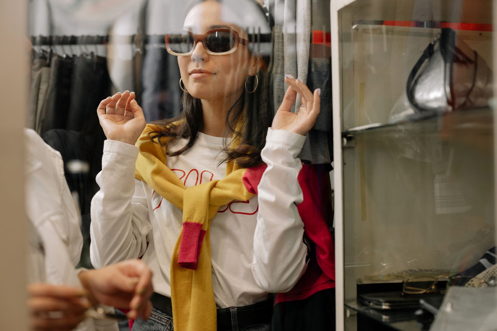 An elegant woman in sunglasses trying on clothes in a bright boutique in Cyprus