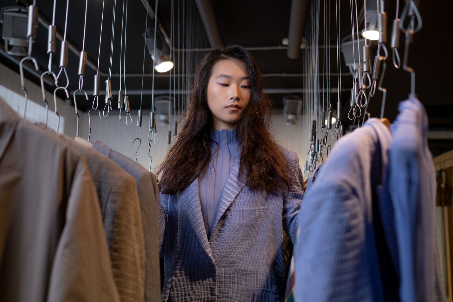 An elegant woman in a tailored blazer looking through clothing rails in a designer boutique in Cyprus